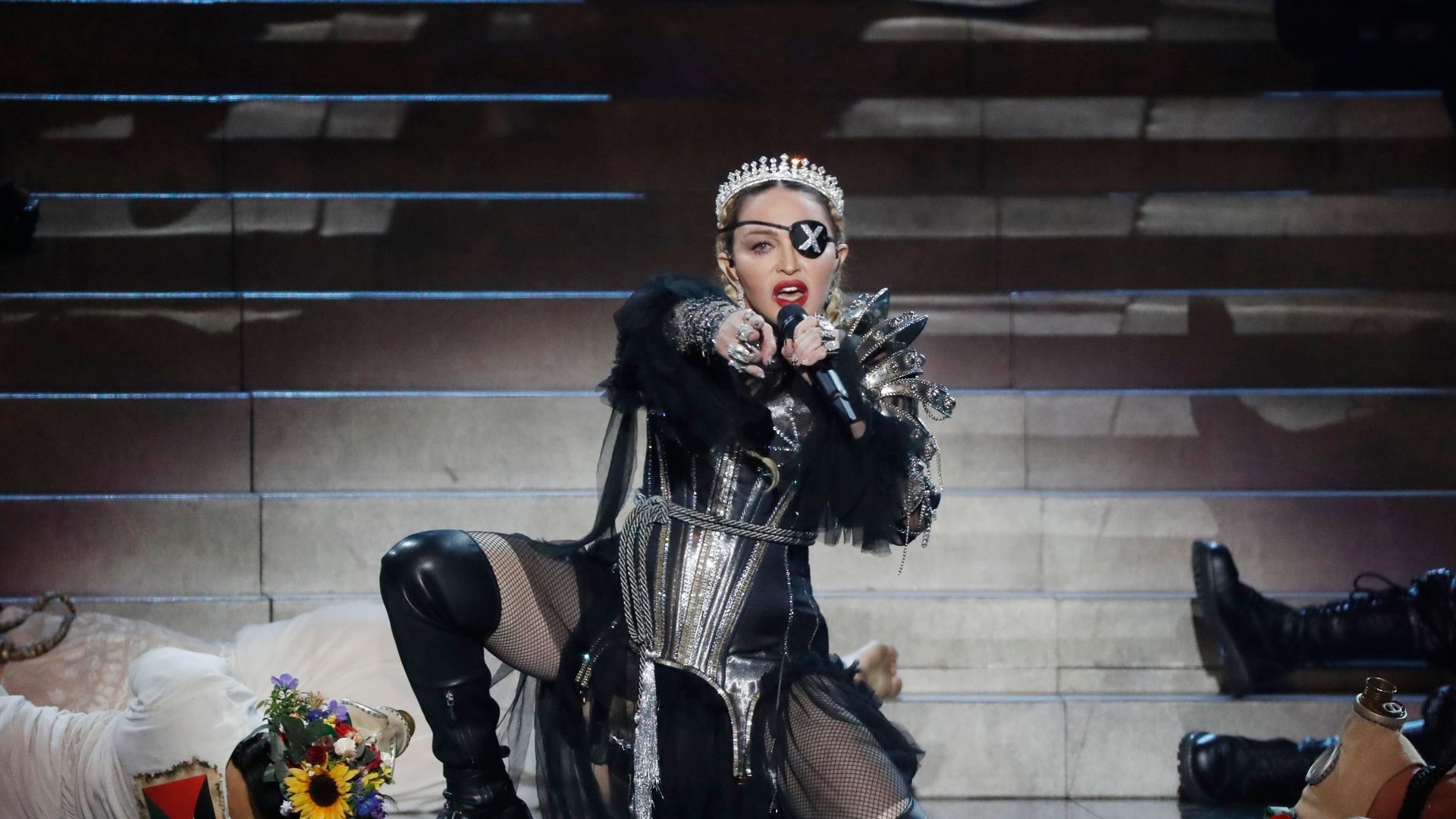 Madonna performs at Eurovision in a Gaultier silver corset, fishnets, an X-eyepatch and crown, creating a cyber-medieval rebel queen look.