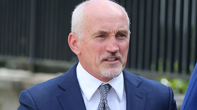 Barry McGuigan in a blue suit frowning outside