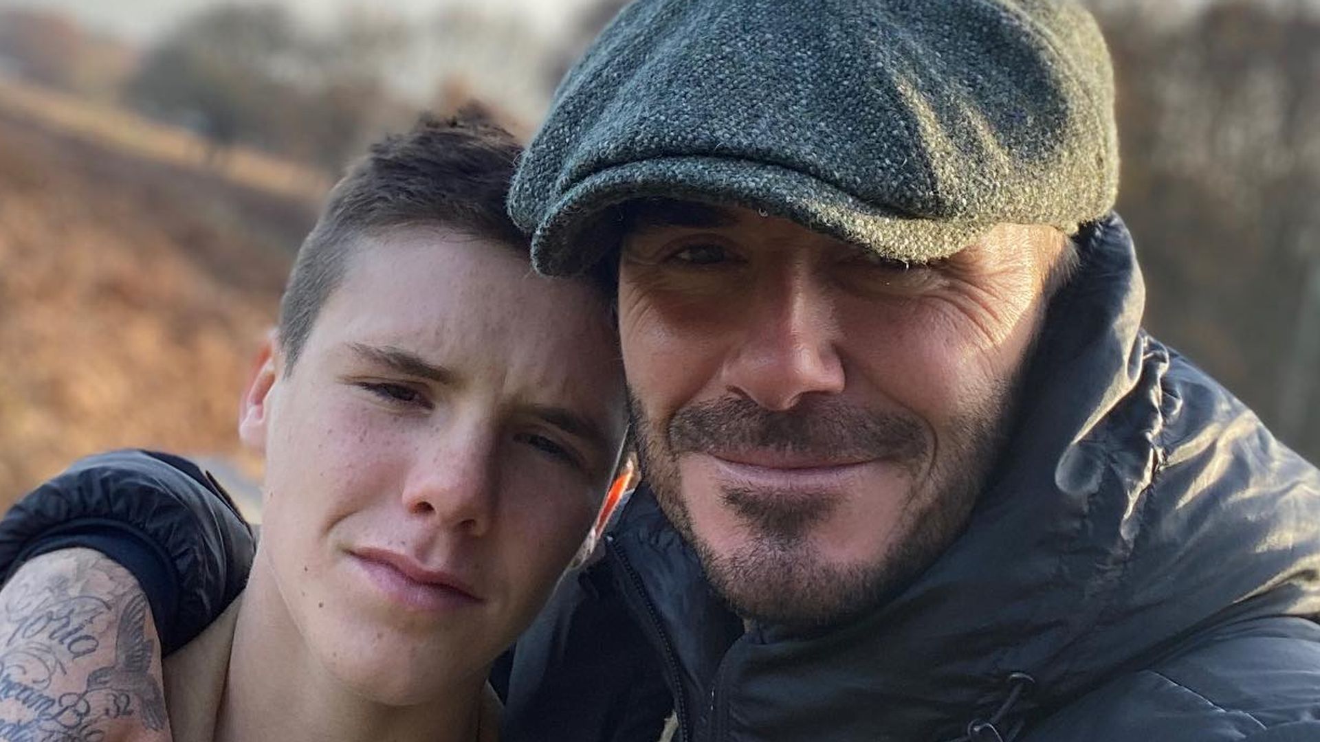 father posing outdoors with son