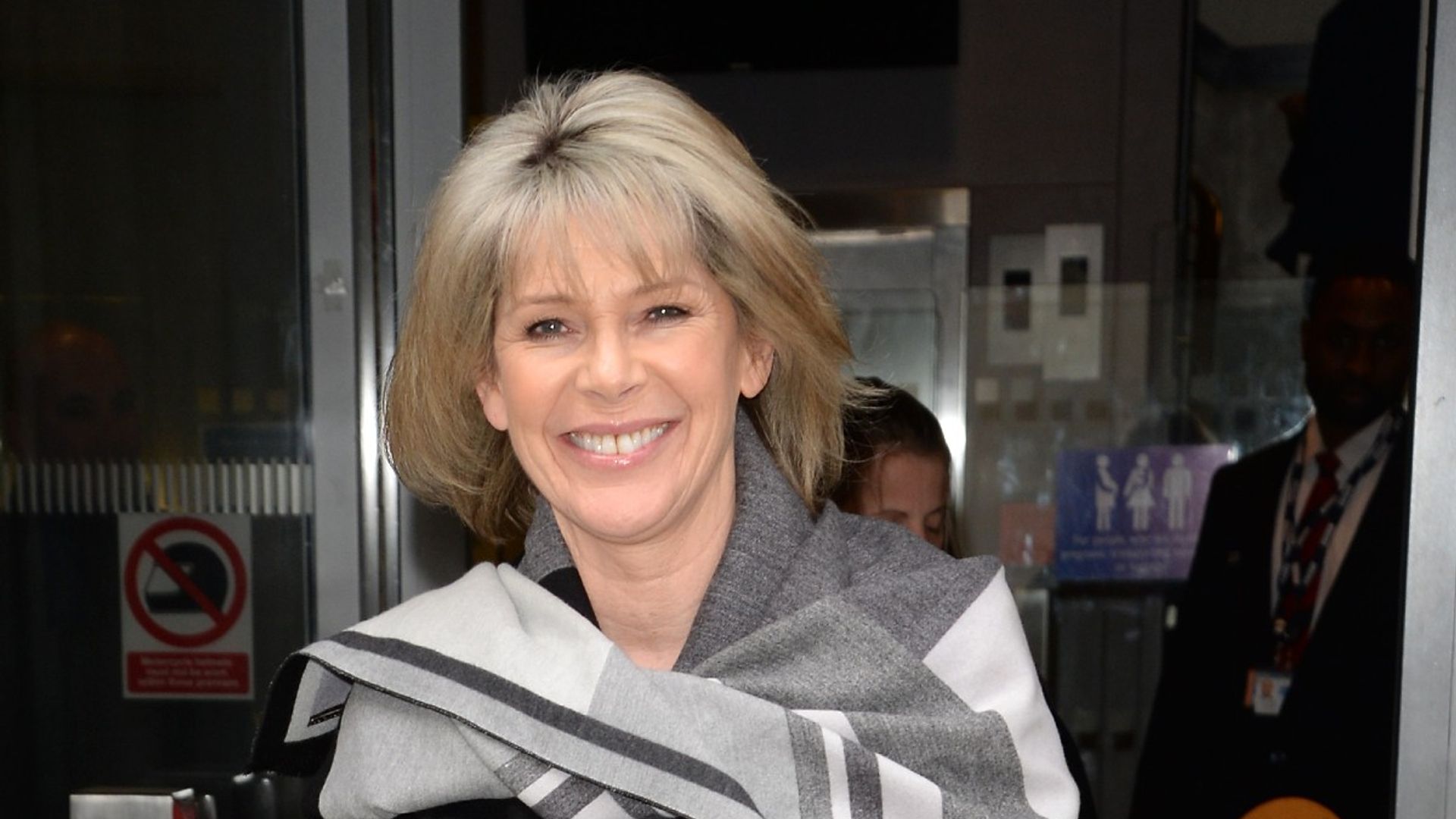 Ruth Langsford smiling as she walks out of a building