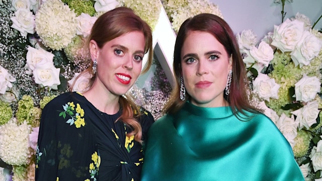 Beatrice and Eugenie wearing evening dresses in front of a flower wall