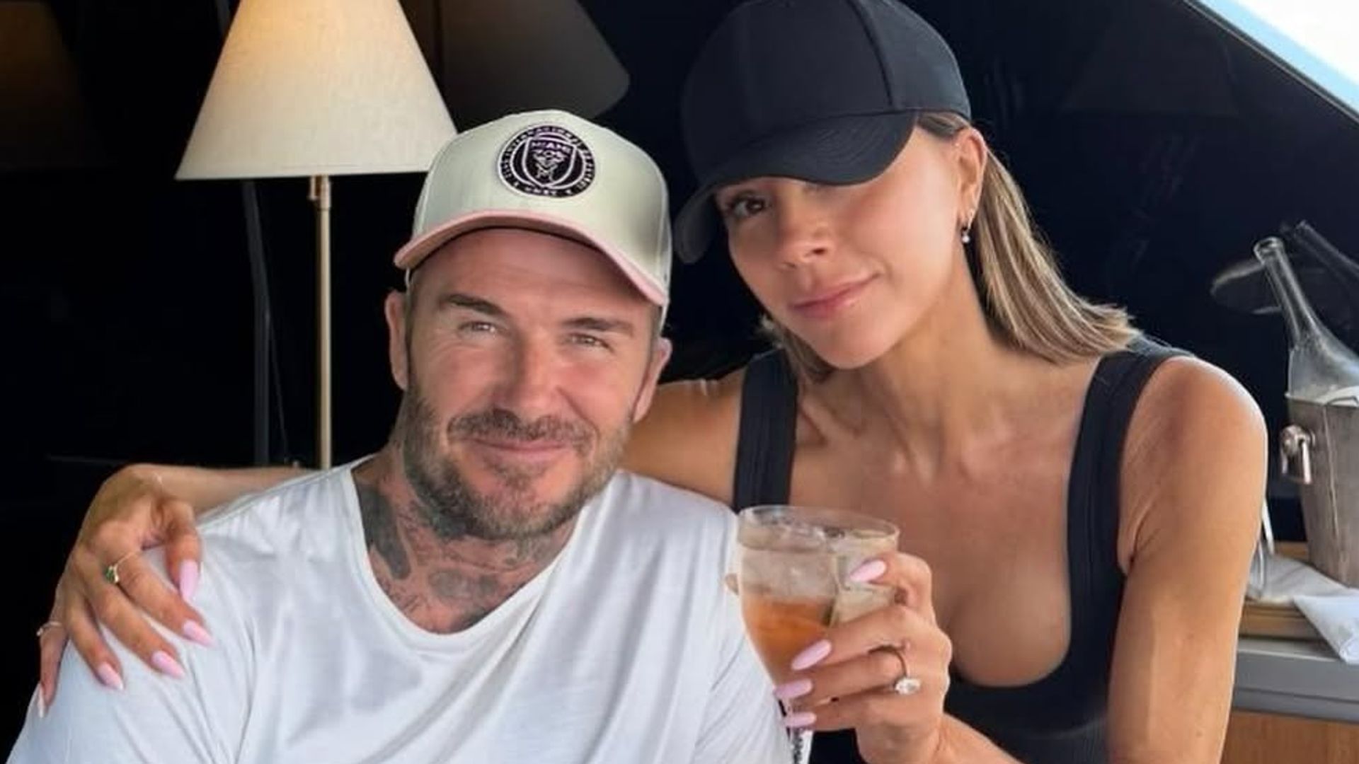 David and Victoria Beckham hold up drinks while sitting on a boat near their Miami home