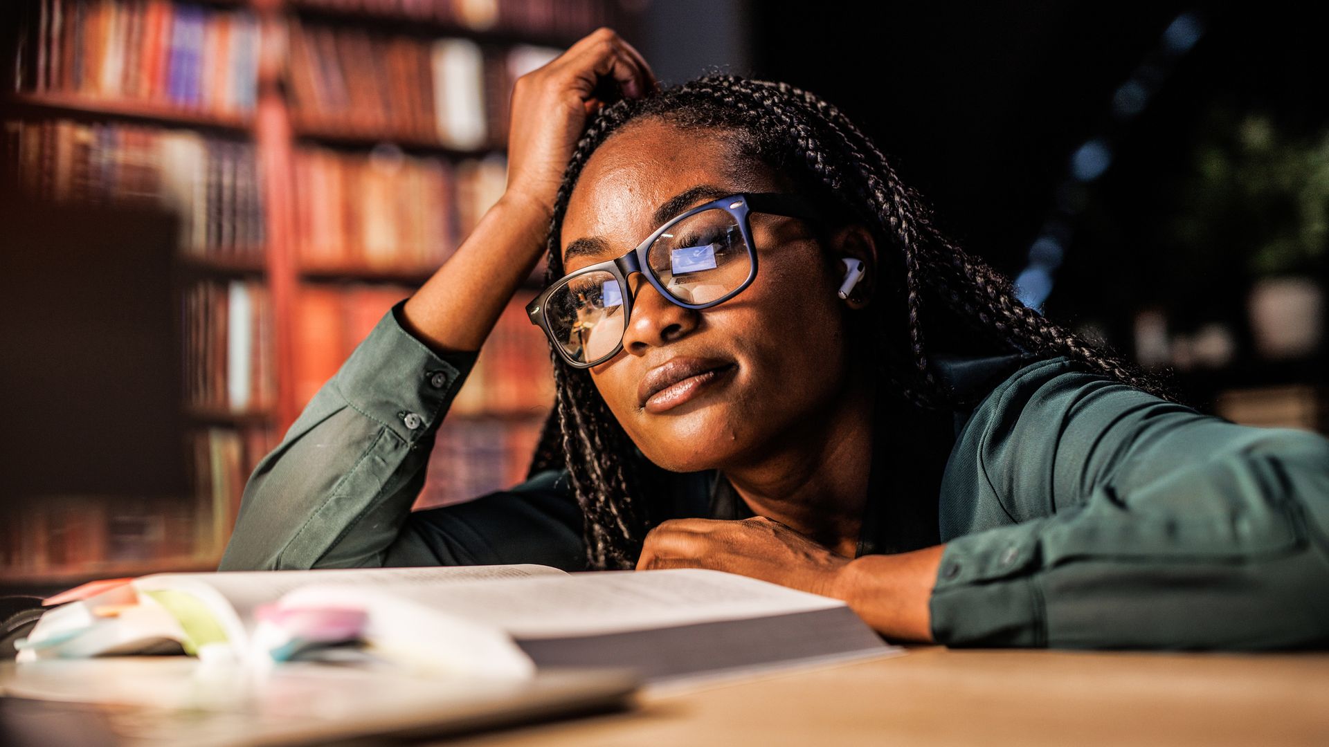 Black female student studying in a library, working late 