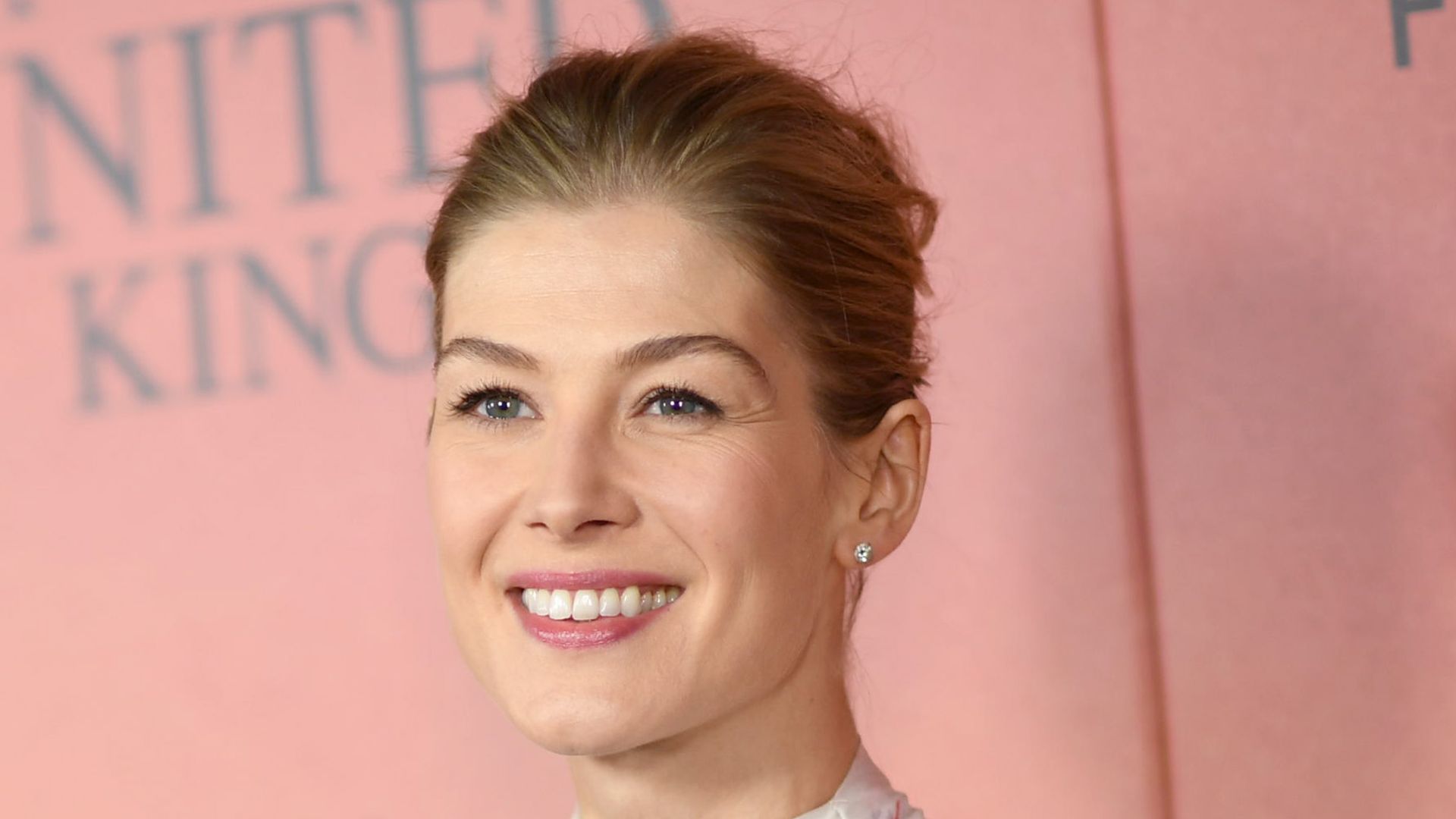 Rosamund Pike smiling in a white dress