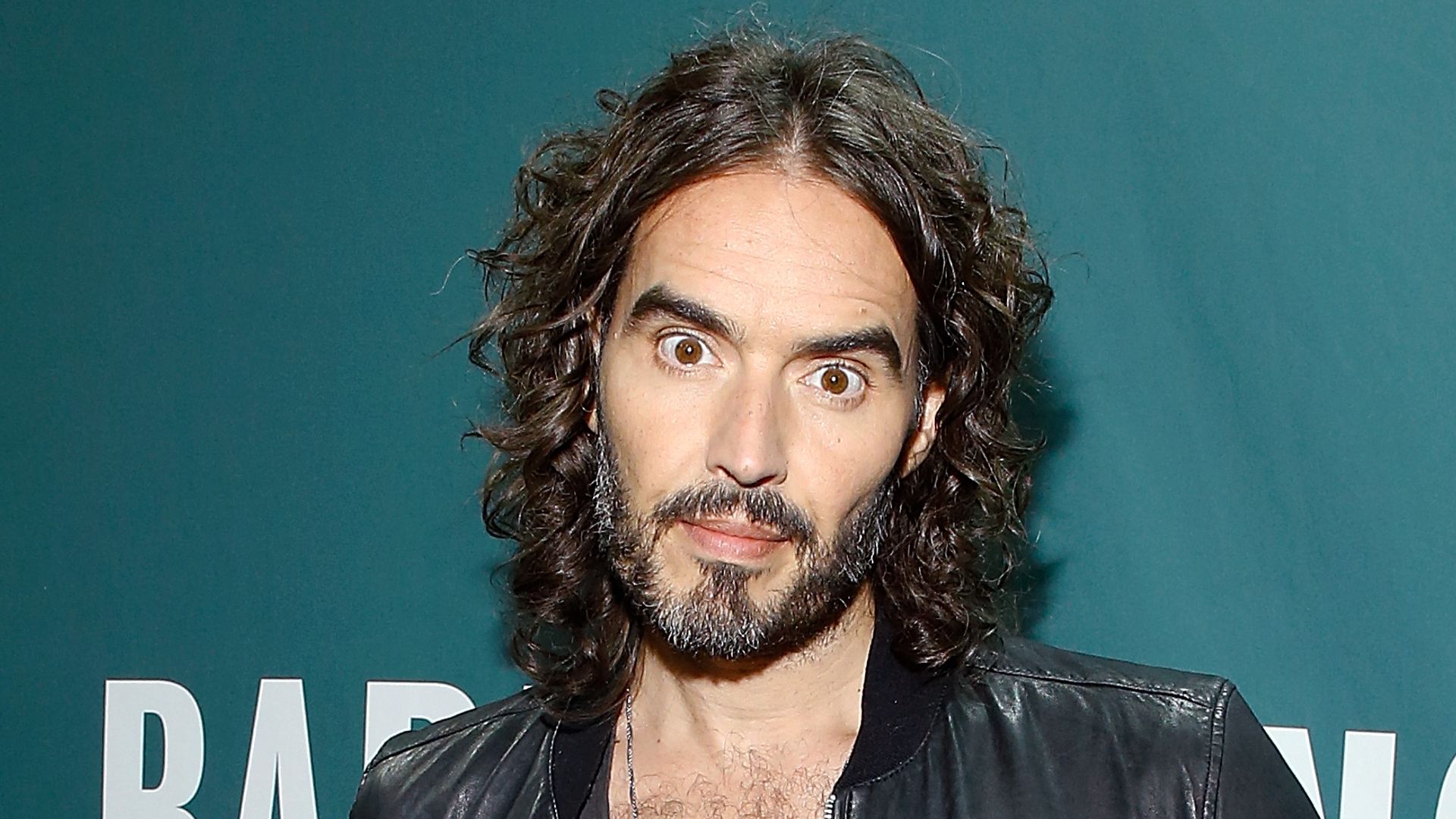Russell Brand in leather jacket and shirt