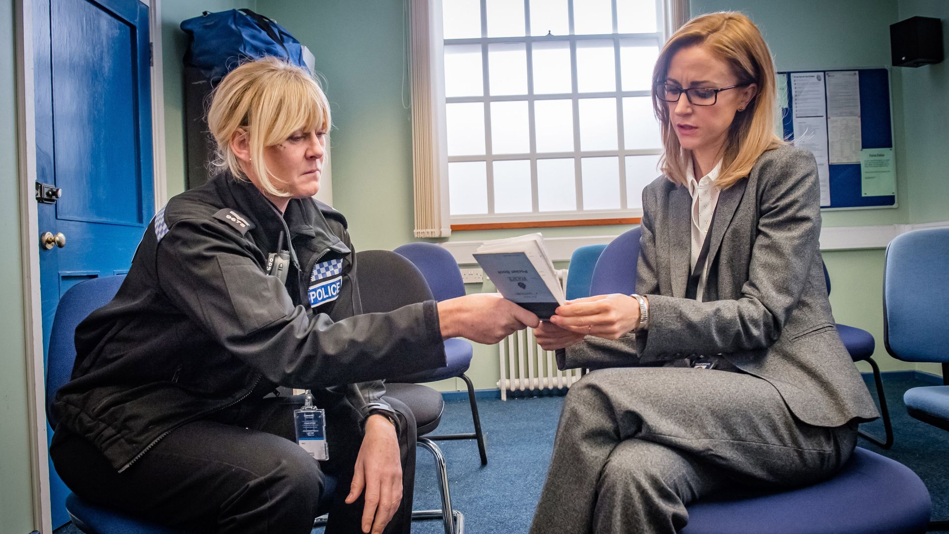 police officer and lawyer looking at book in station