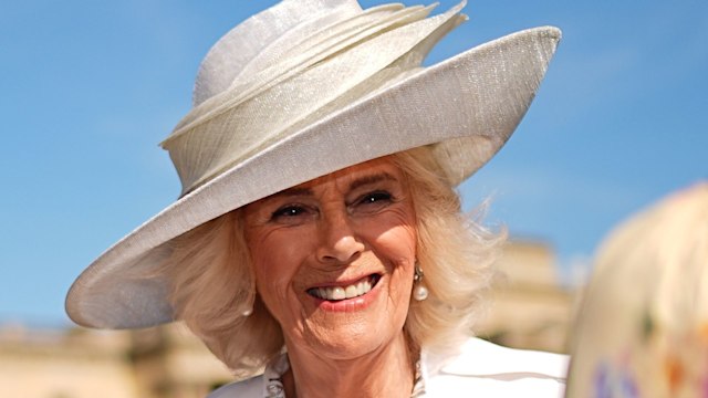 Queen Camilla smiling in a white outfit