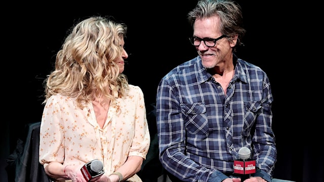 Kevin Bacon and Kyra Sedgwick smiling at each other while sat on stage being interviewed