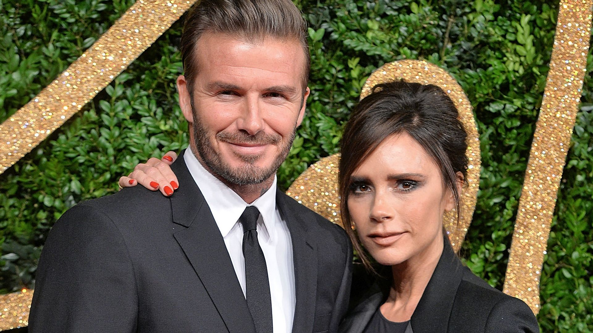 Victoria and David Beckham smile at the camera at a red carpet event