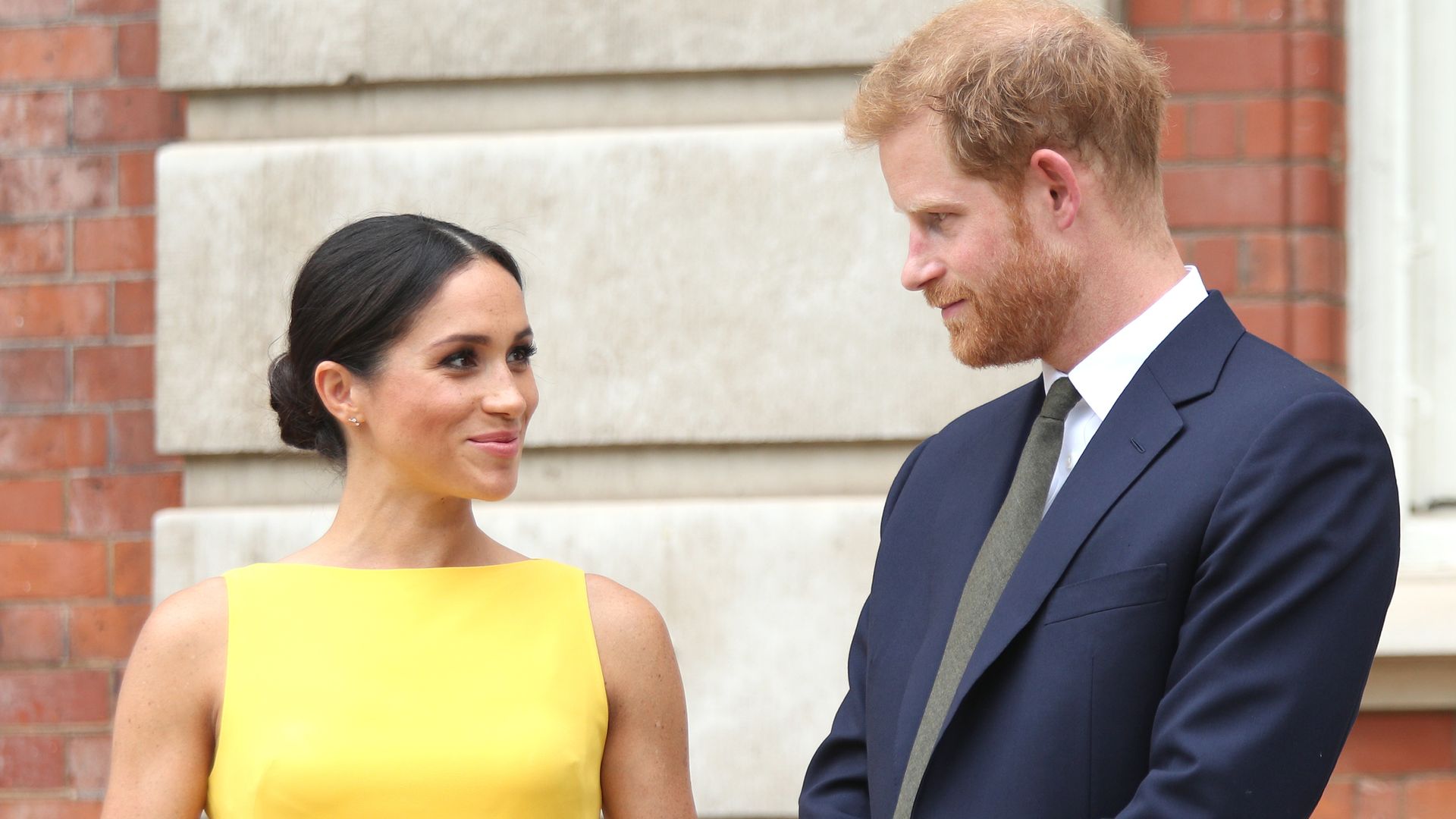 Meghan Markle in a yellow dress with Prince Harry in a suit