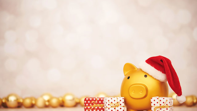 Piggy bank wearing a Santa hat for the holidays. Gifts and gold ornaments 