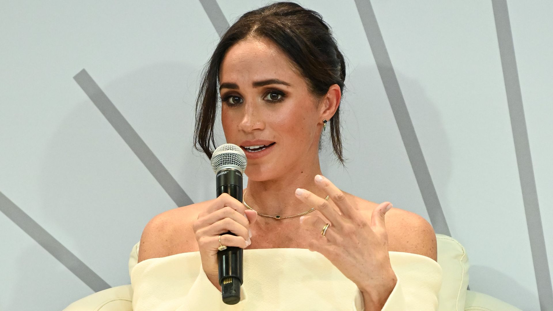 Meghan Markle wearing cream and holding microphone