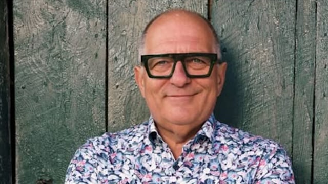 man with floral shirt and thick reading glasses