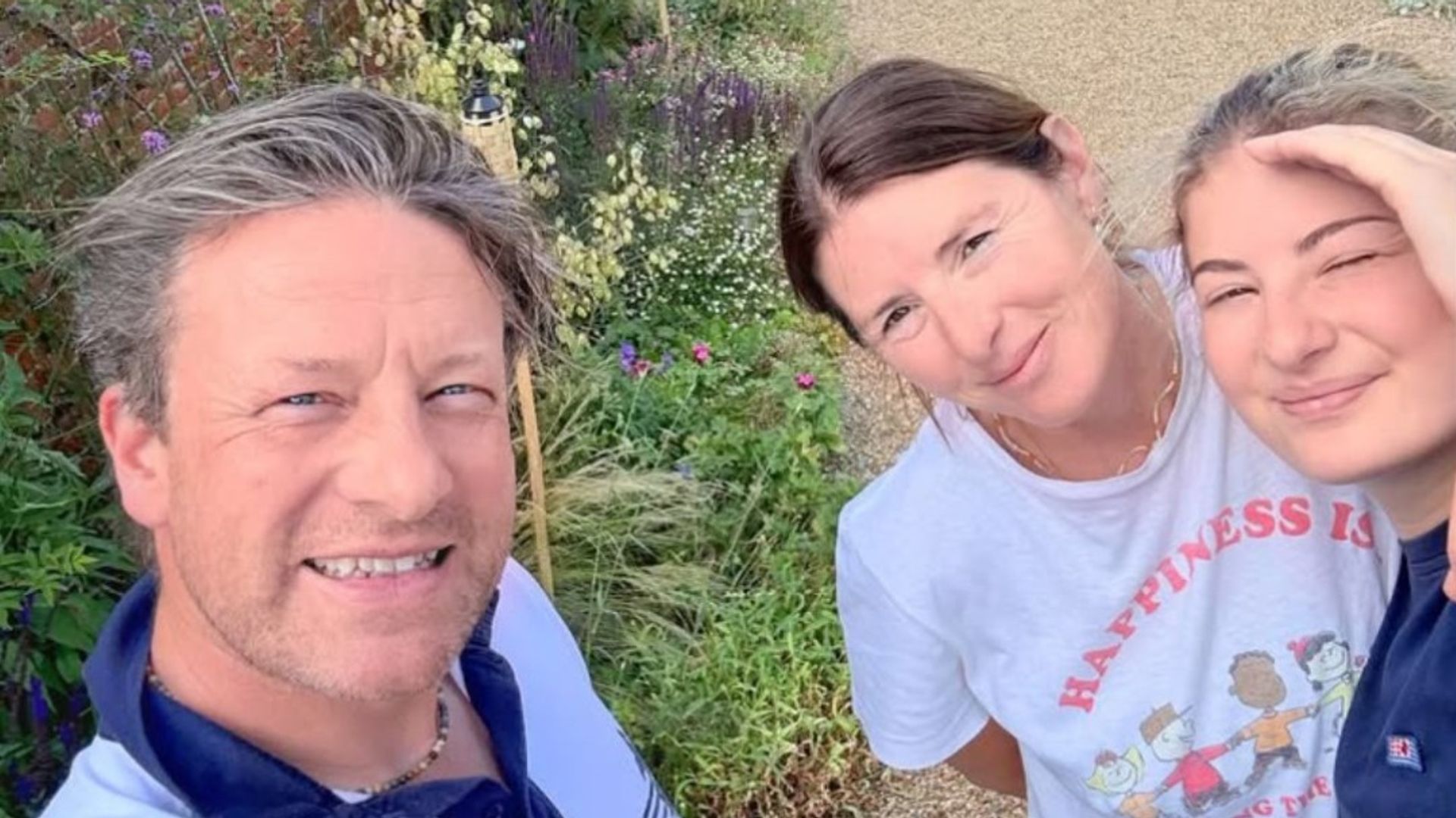 Jamie Oliver takes a selfie next to his wife, Jools and daughter Poppy with their garden in the background