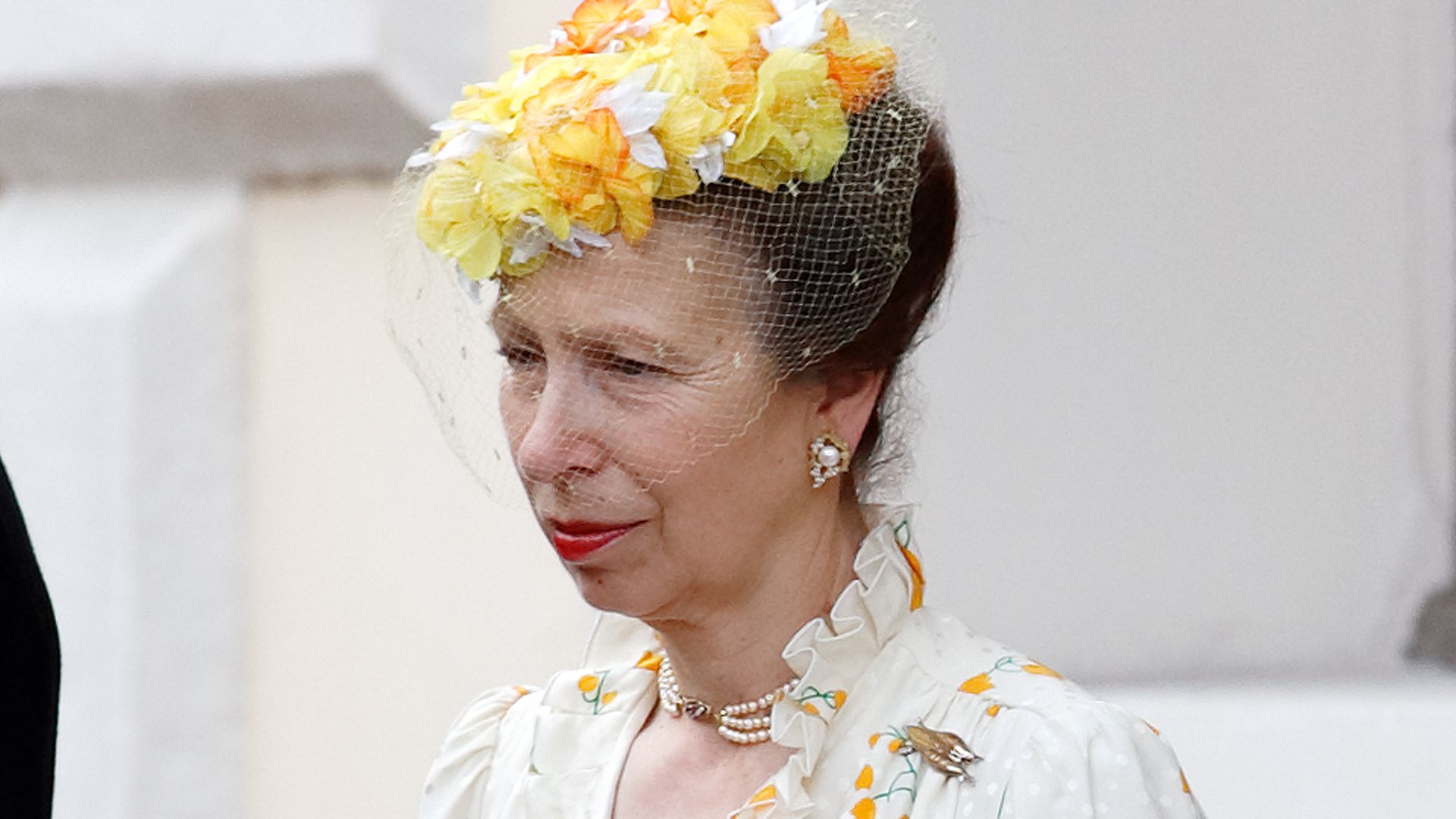 Princess Anne in a white ruffled dress and yellow headpiece