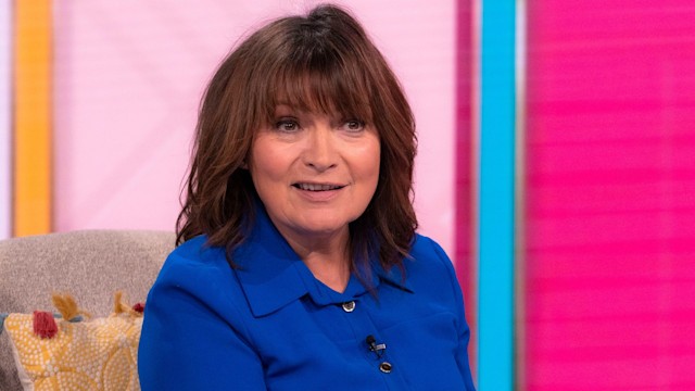 Lorraine in a blue shirt sitting on armchair while filming her TV talkshow