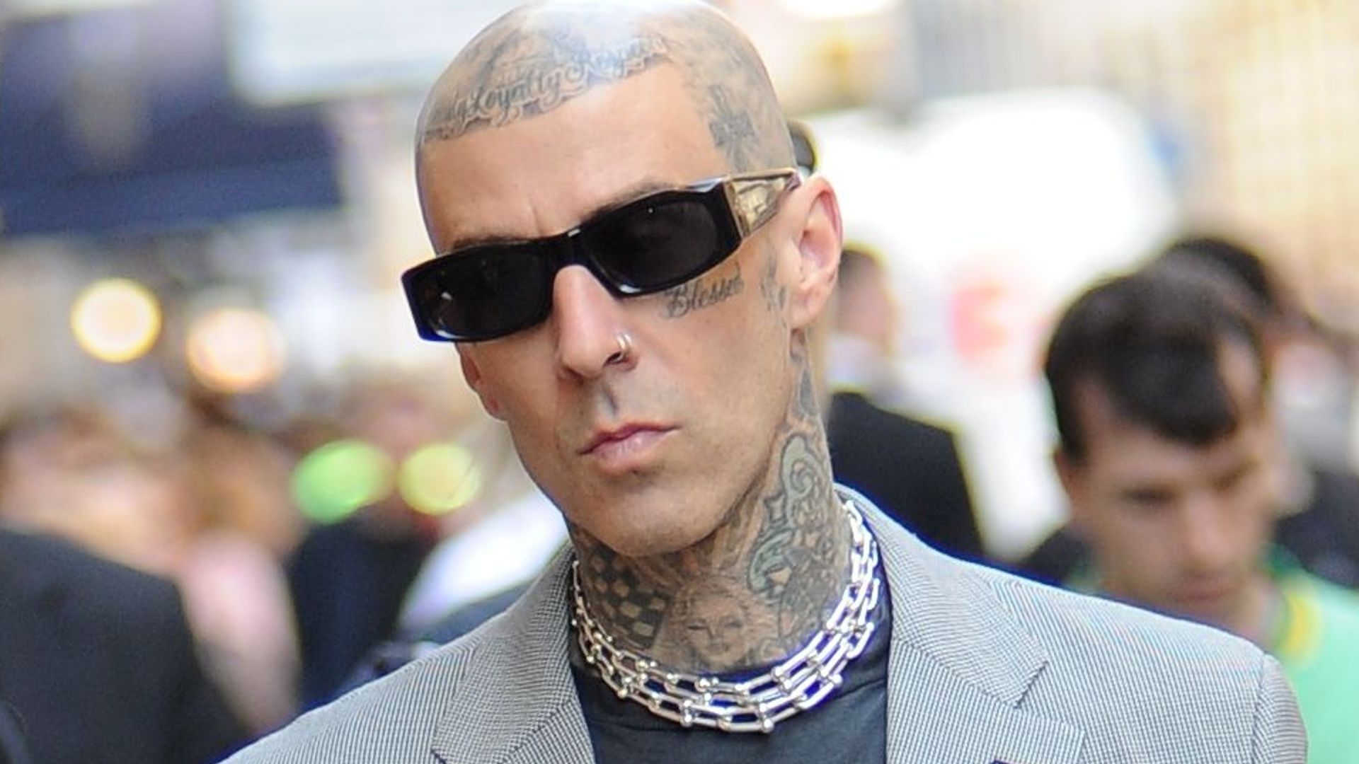 Travis Barker in a grey jacket and sunglasses 