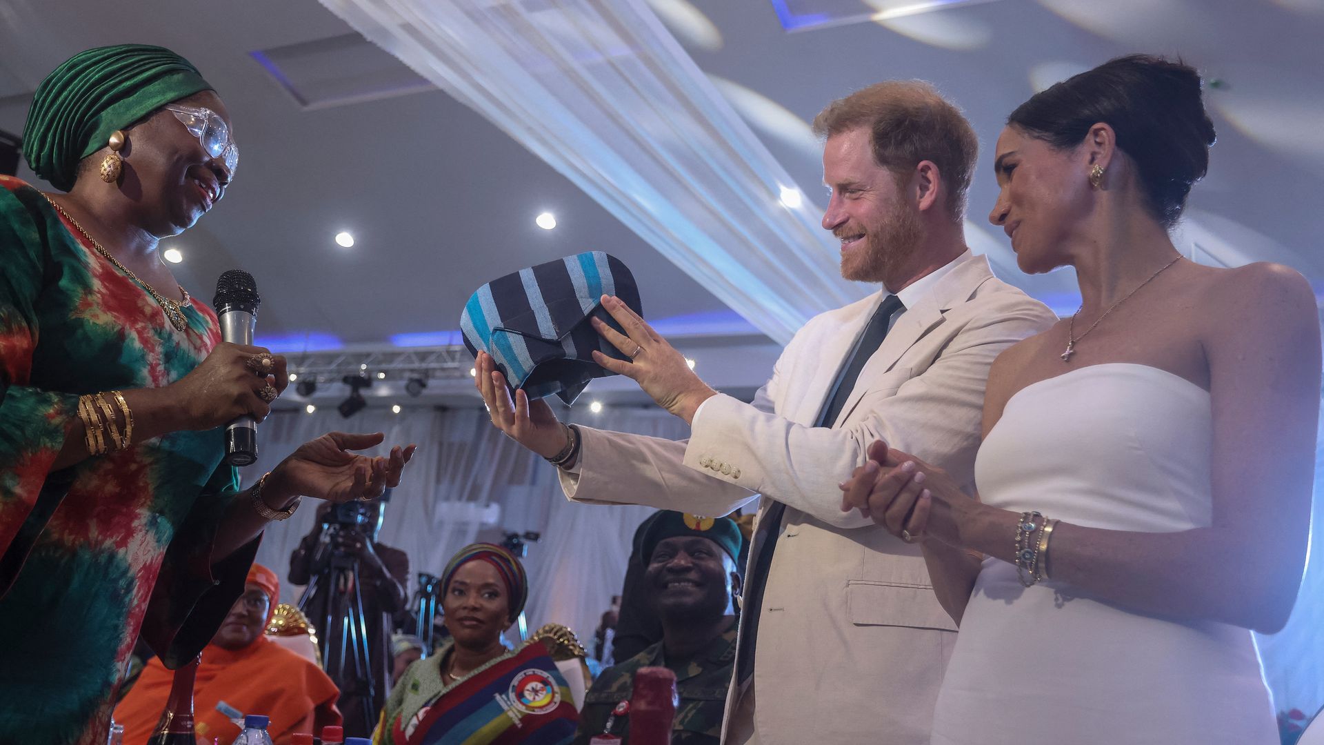 Prince Harry and Meghan Markle receive a traditional outfit made in Nigeria as they attend lunch at the Nigerian Defence Headquarters in Abuja