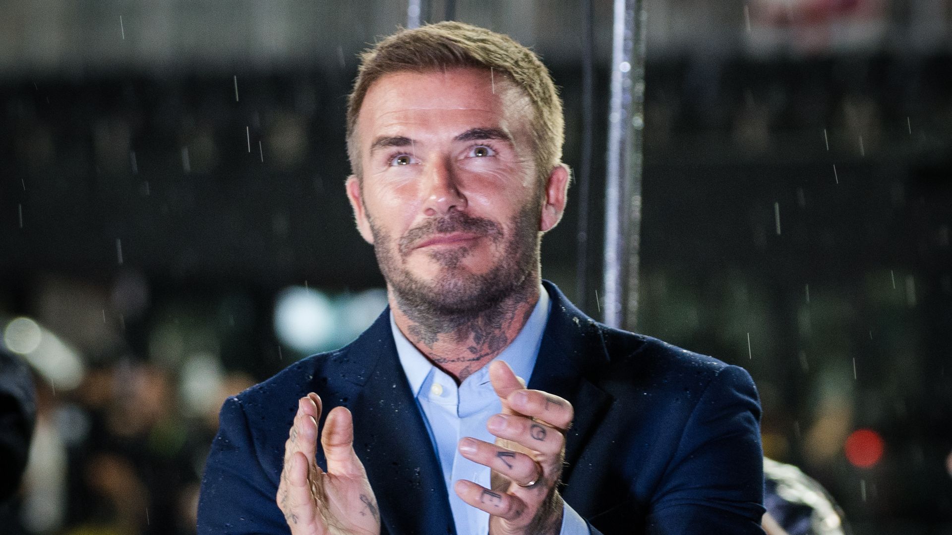 David Beckham clapping in a suit in the rain