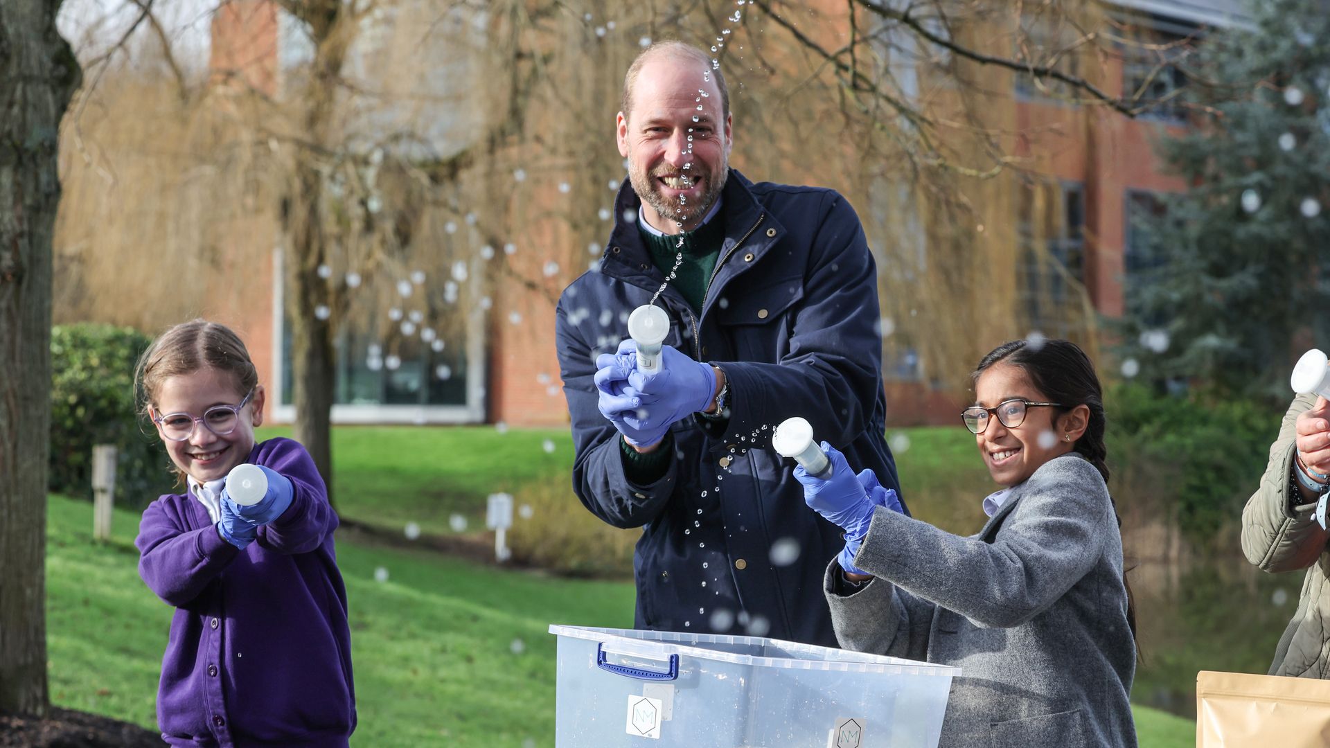 William laughing as he squirts pond water at journalists