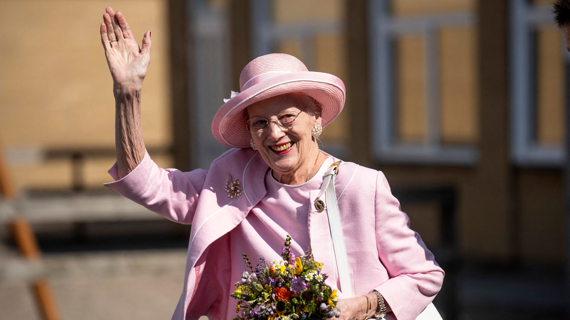 Queen Margrethe waving in pink outfit and hat