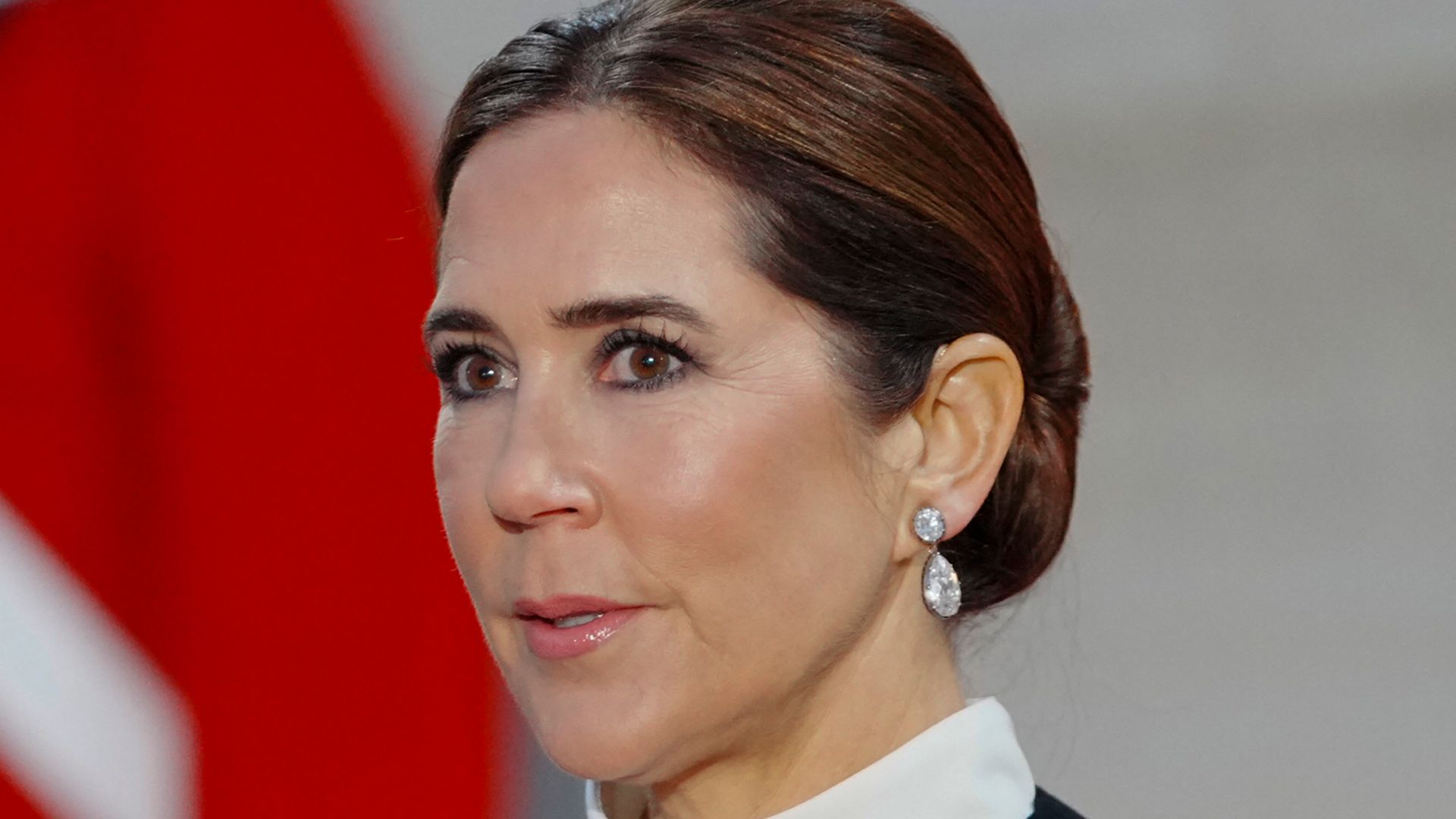 Queen Mary wearing white high-necked top and black coat with diamond earrings