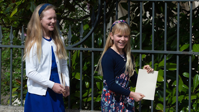 Savannah Phillips in a white coat and blue dress with Isla Phillips in floral trousers and blue cardigan