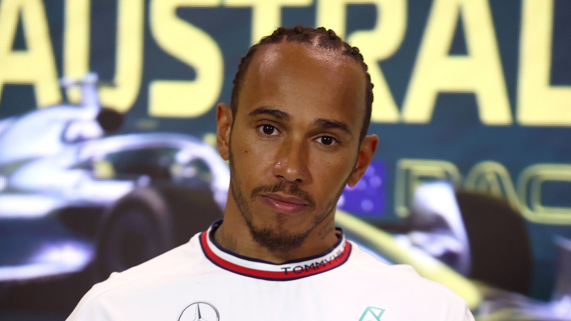 Lewis Hamilton in a white top with a microphone