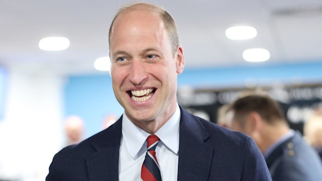 Prince William in a suit holding a mug