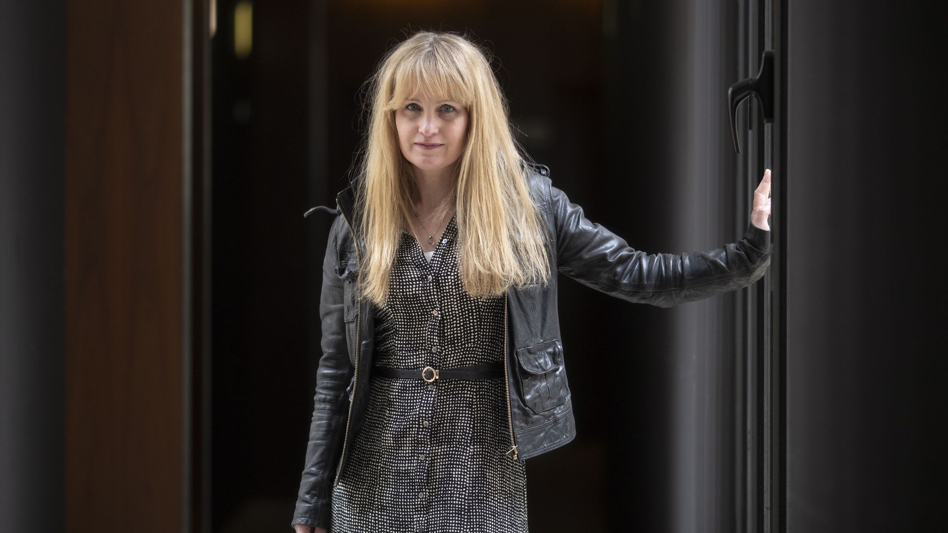 Cat Jarman in a leather jacket and a plaid dress