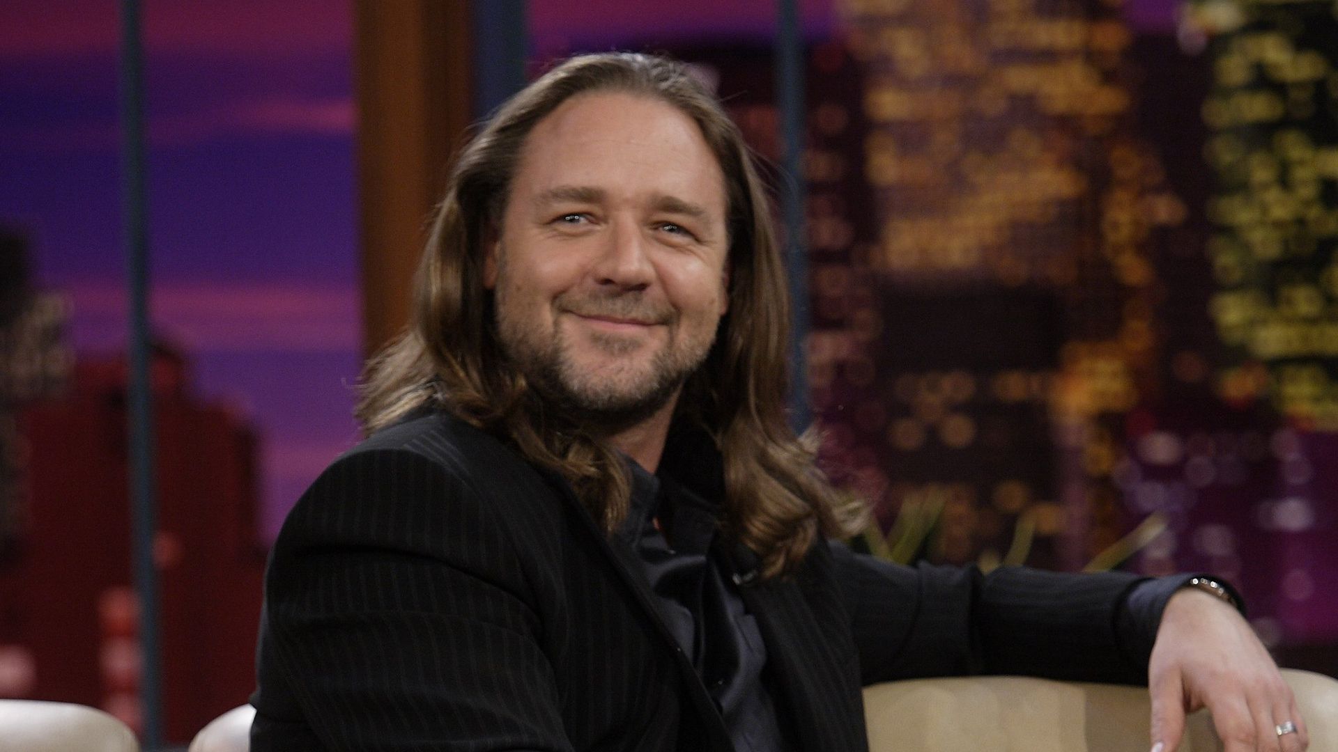 Russell Crowe in black suit with long hair