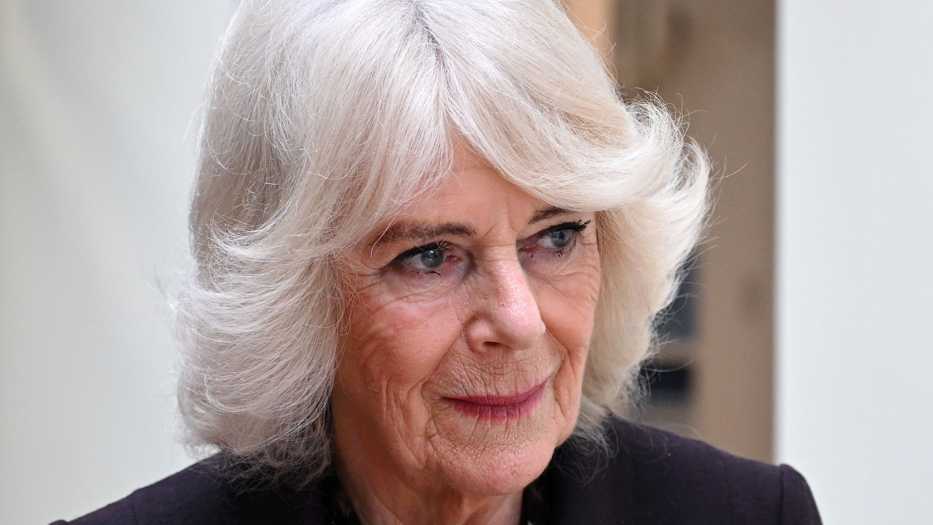 Queen Camilla in a black coat with pink lipstick
