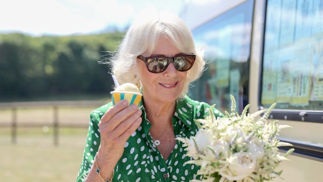 Queen Camilla smiles with a bouquet of flowers and an ice cream