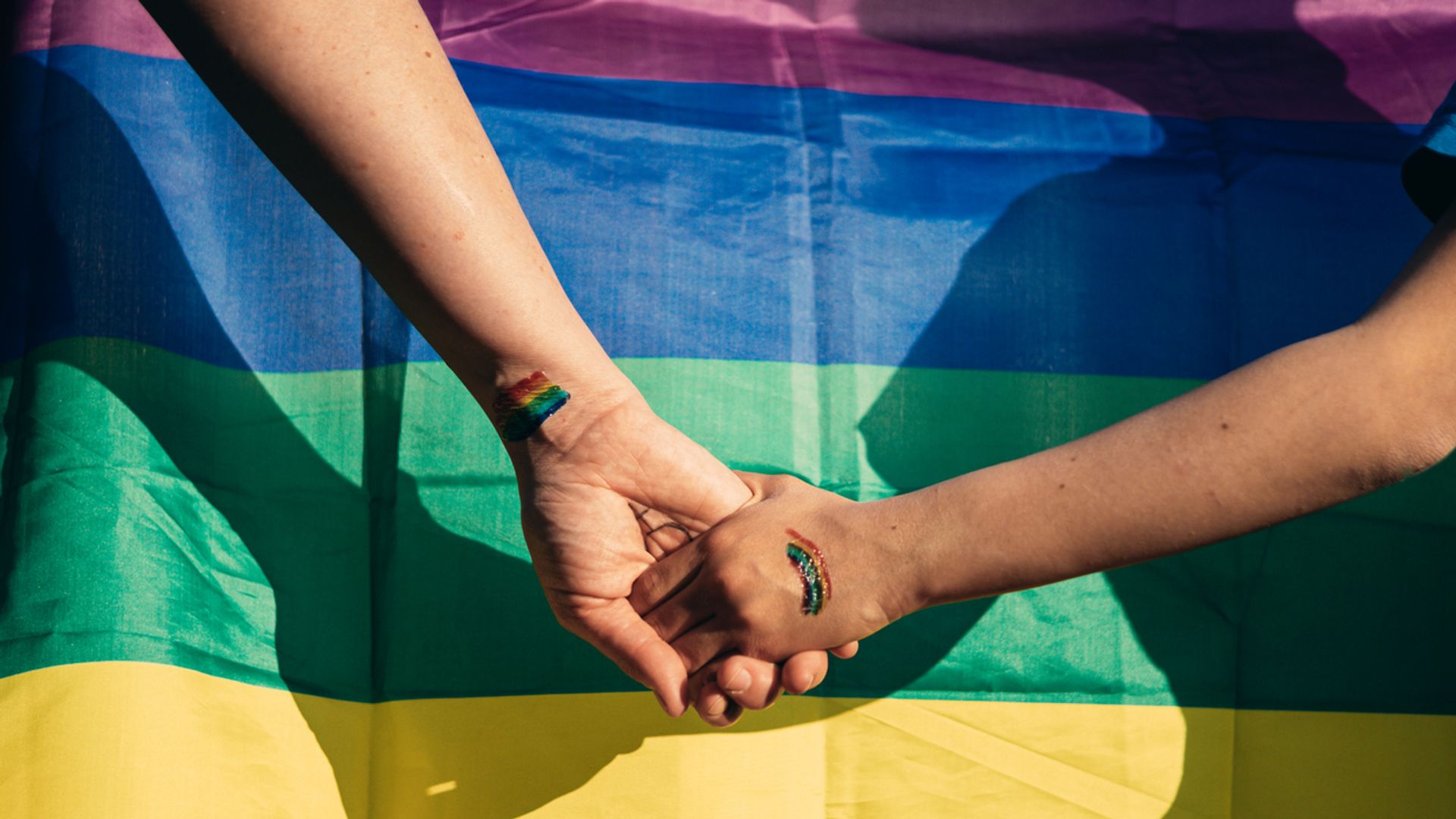 A mother holding hands with her daughter and the gay pride flag