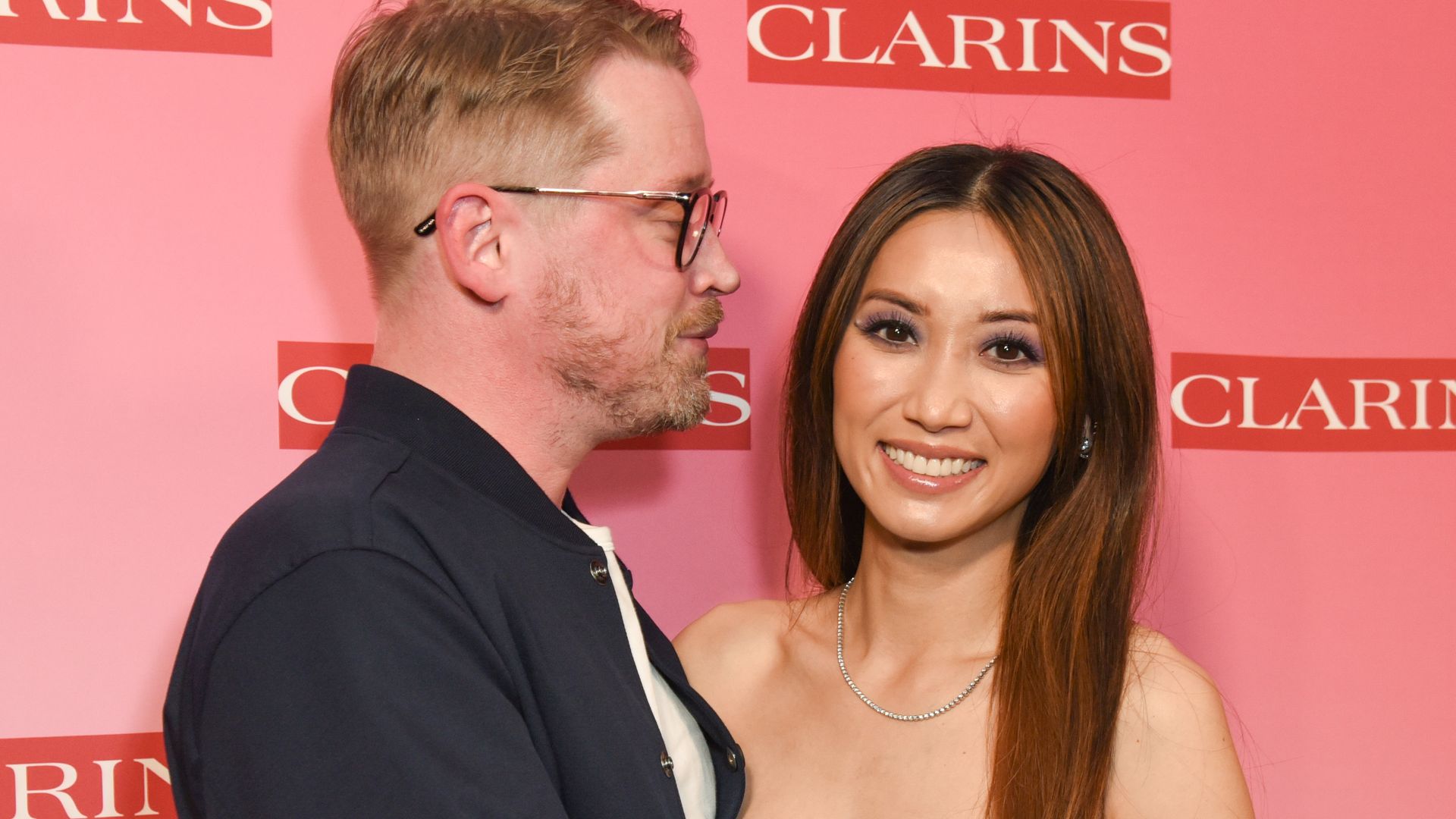 Macaulay Culkin with his arms around Brenda Song in a strapless top
