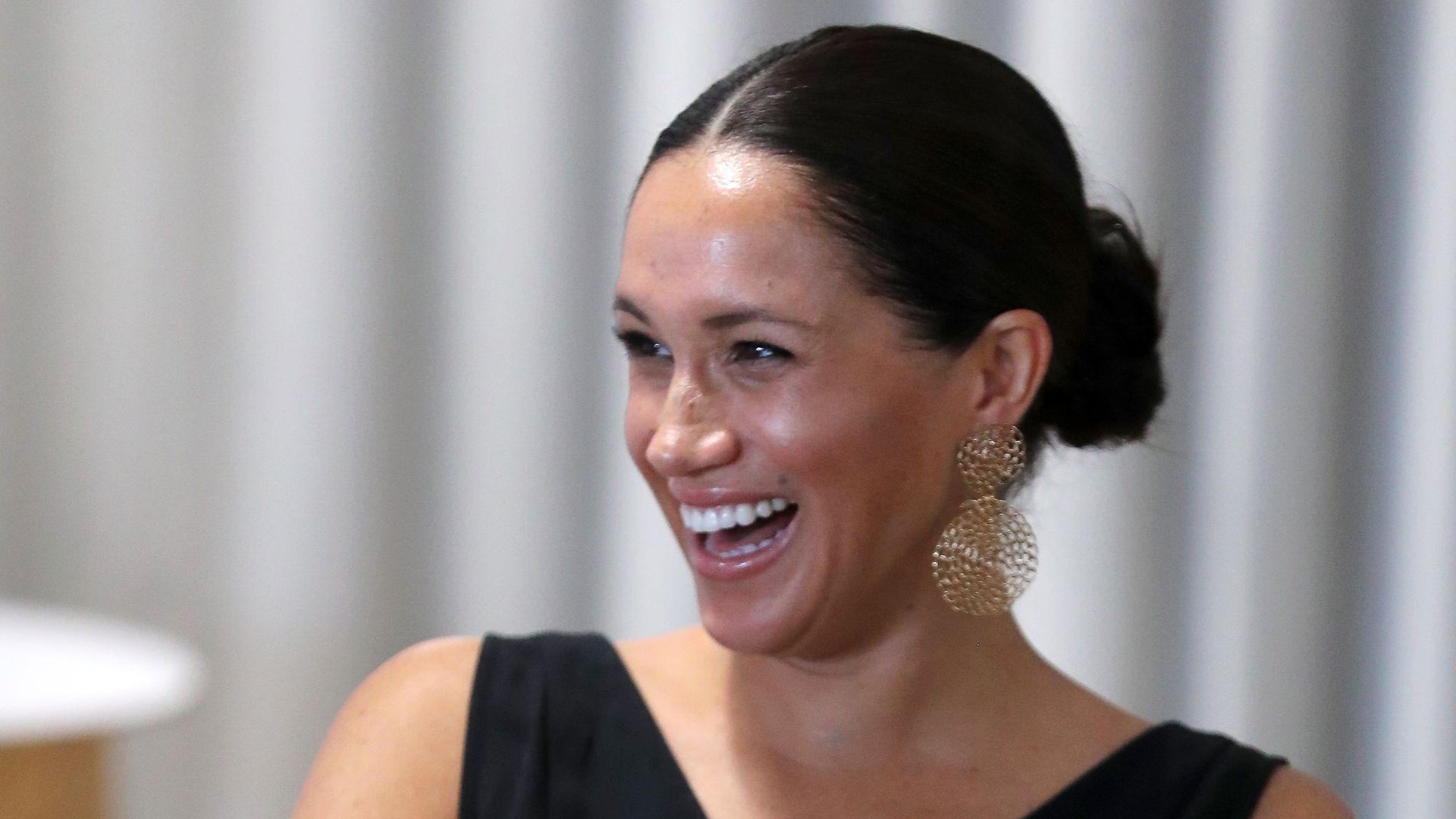 Meghan Markle laughing with gold earrings