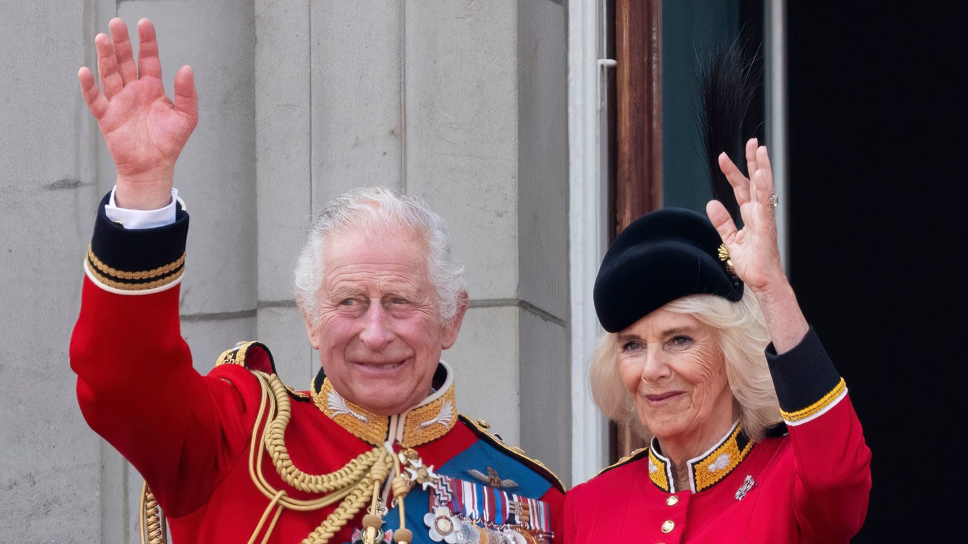 King Charles III and Queen Camilla waving on the royal balcony at Buckingham Palace