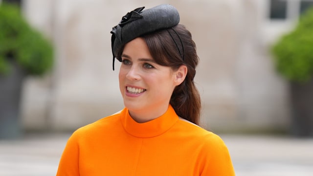 Princess Eugenie wearing orange dress and black hat