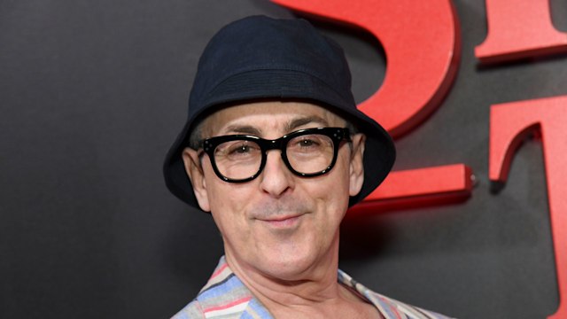 Alan Cumming in a multi-coloured shirt and bucket hat