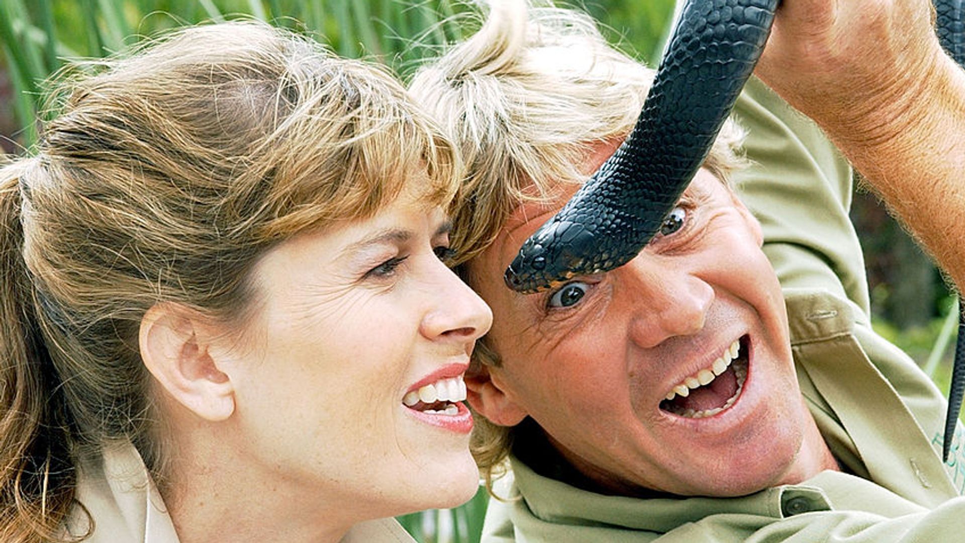 Steve Irwin holding a snake besides Terri Irwin