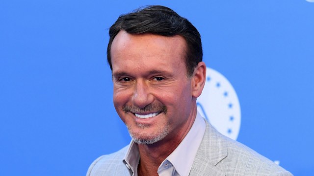 tim mcgraw smiling in grey suit with dark head of hair
