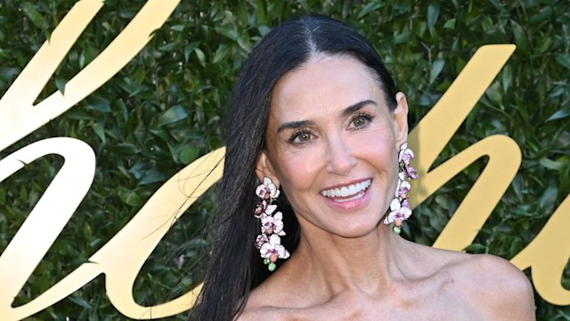 Demi Moore smiling in yellow dress and statement earrings