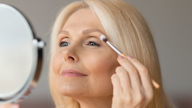 Older woman applying makeup