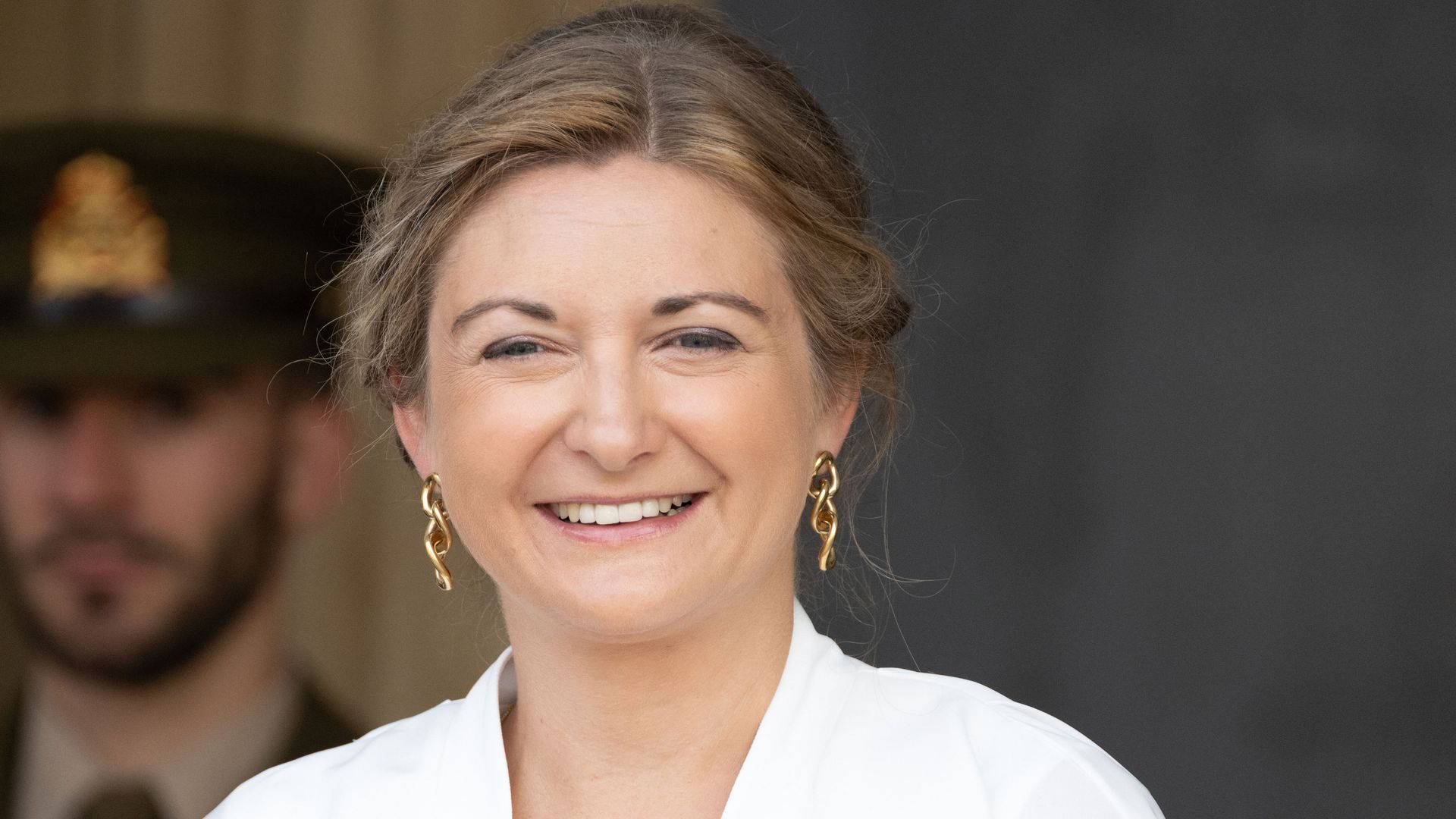 Princess Stephanie smiling in white top and gold earrings