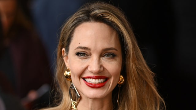 woman smiling in caramel top and gold earrings