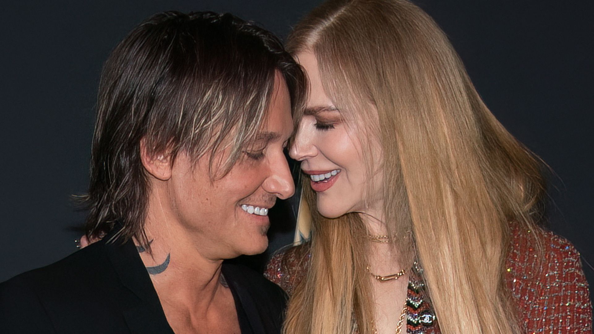 Nicole Kidman and Keith Urban laughing and smiling at each other on a red carpet