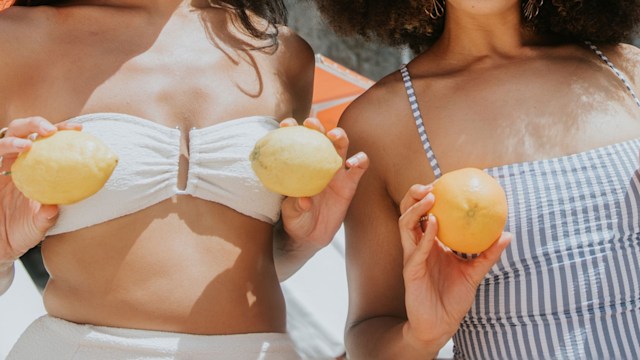 Two women holding lemons in front of their chests 