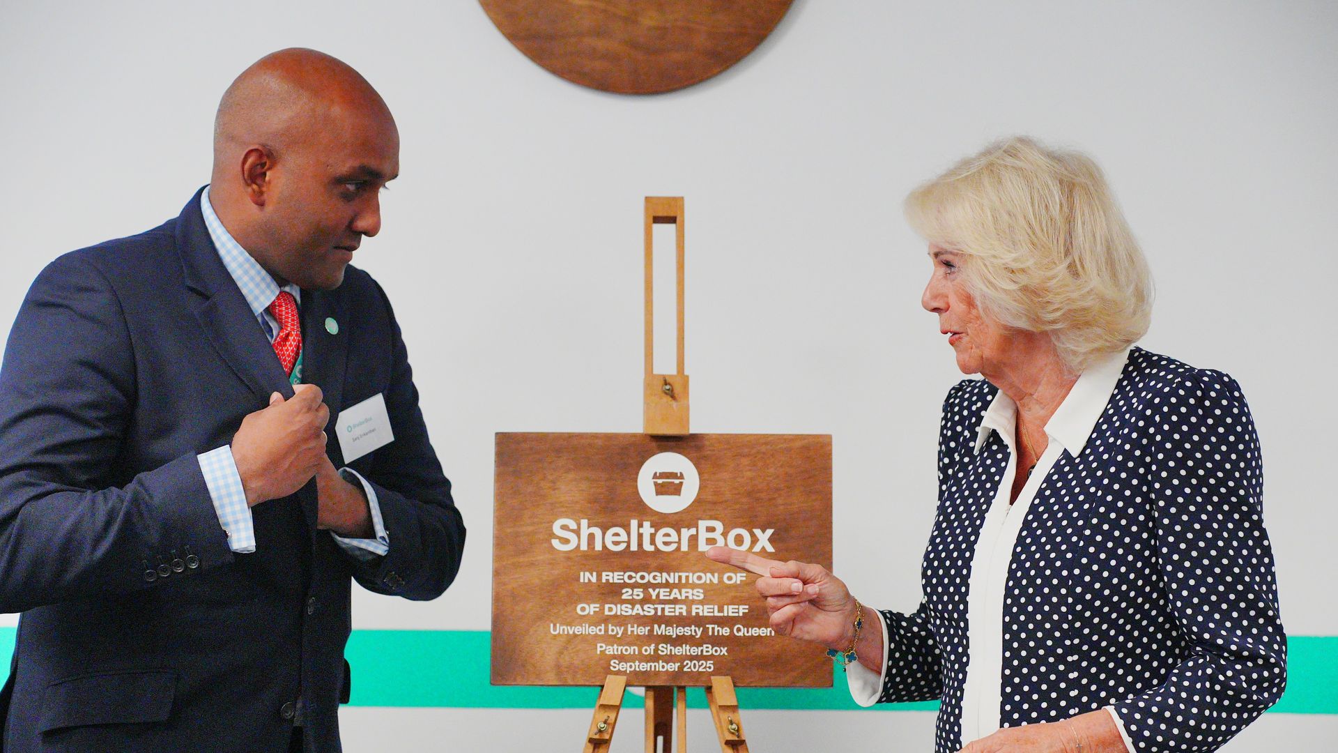 Queen Camilla and a man next to a wooden plaque
