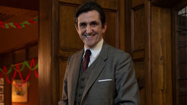 Man in grey suit carving turkey at Christmas