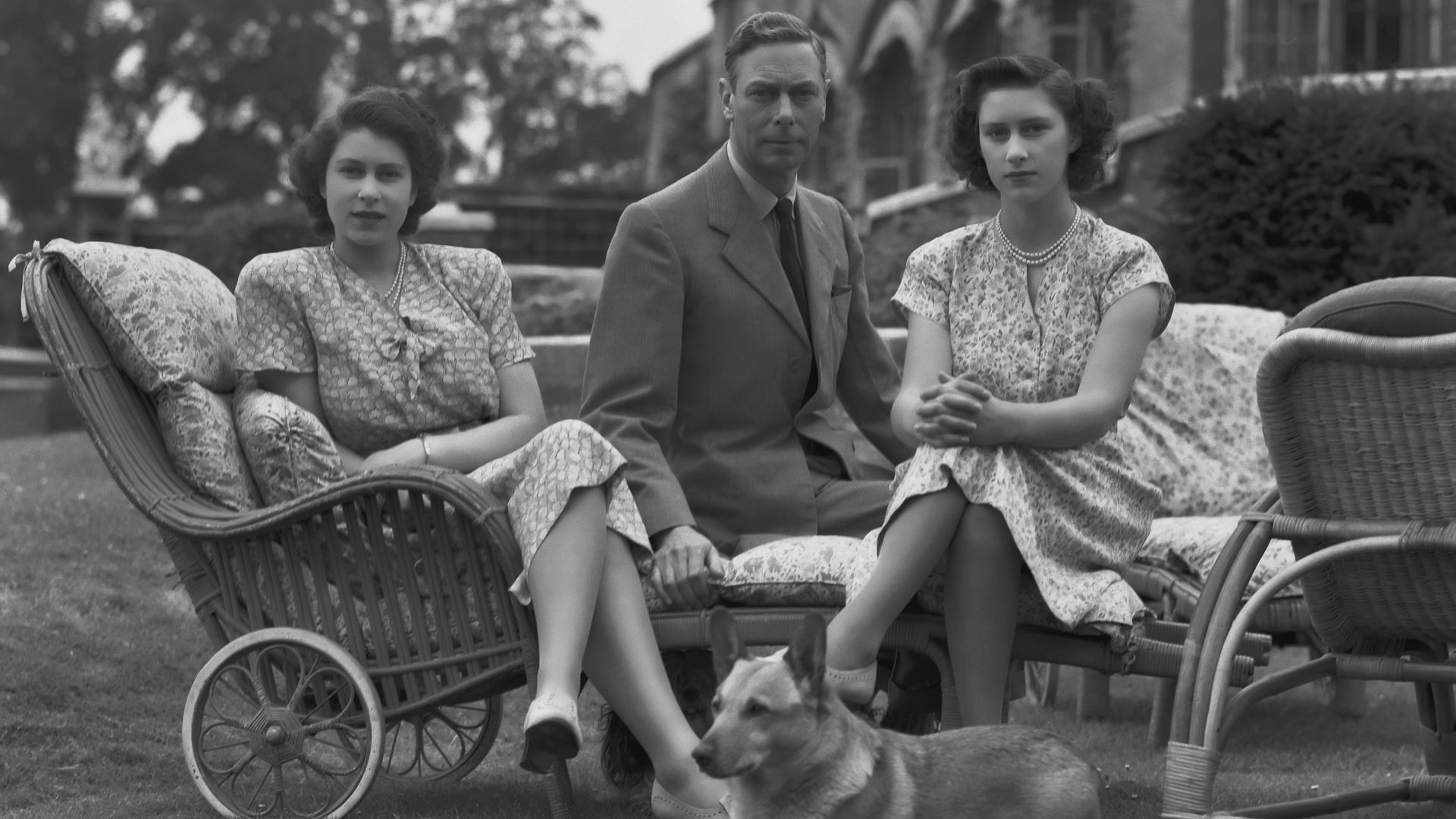A young Queen Elizabeth and Princess Margaret sat with King George VI and a corgi